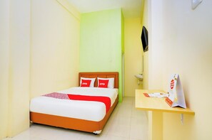 Una habitación de hotel con una cama, un escritorio pequeño, un espejo y un televisor montado en la pared.