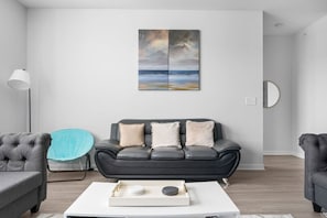 A modern living room with a grey sofa, a white coffee table, and a blue chair. - Affordable 2-bedroom Fishers Pool View (Fishers)