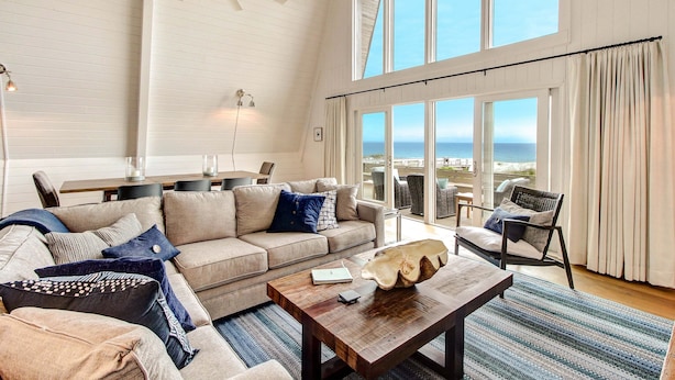 A spacious living room with a large window, a ceiling fan, and a view of the ocean. - 1896 S Fletcher Ave (Fernandina Beach)