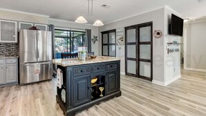 A modern kitchen with a central island, stainless steel appliances, and a large window. - 2113 Talbot Ct (Fernandina Beach)