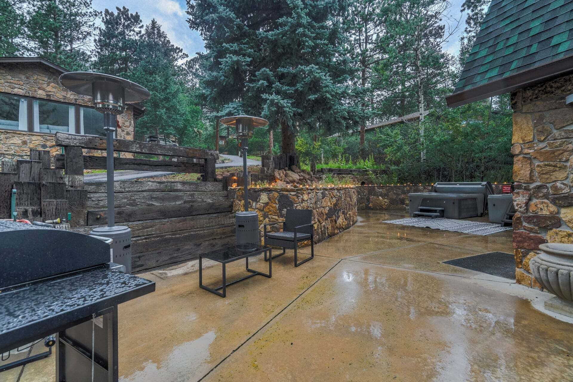 Une terrasse extérieure avec un mur en pierre, un barbecue et des sièges.