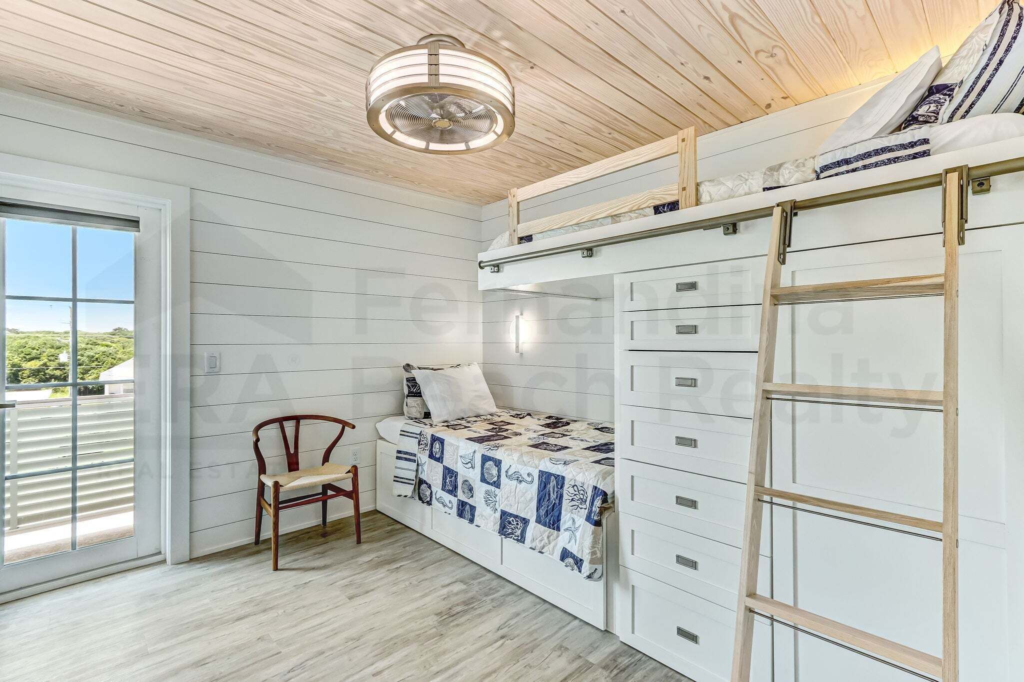 A room with a bunk bed, a chair, a desk, and a ladder.
