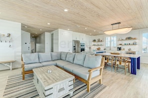 A modern kitchen with white cabinets, a built-in oven, and a dining area with a wooden table and chairs. - 226 South Fletcher 3rd Floor (Fernandina Beach)
