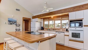 Een moderne keuken met een houten kookeiland, witte kasten en uitzicht op de omgeving.