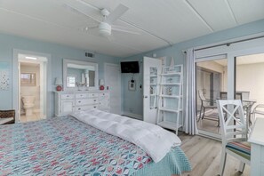 A bedroom with a bed, dresser, TV, and a balcony.