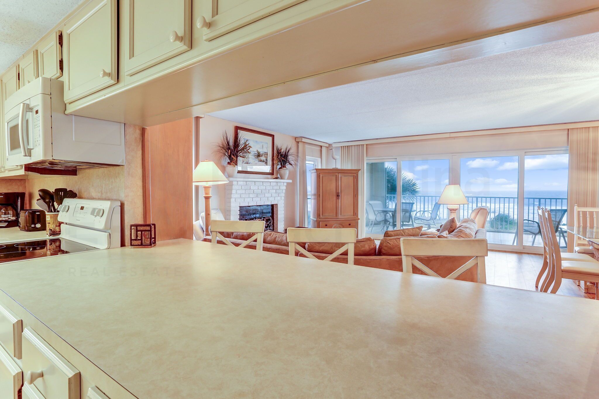 A spacious kitchen with a large island, a fireplace, and a dining area with a view of the ocean.