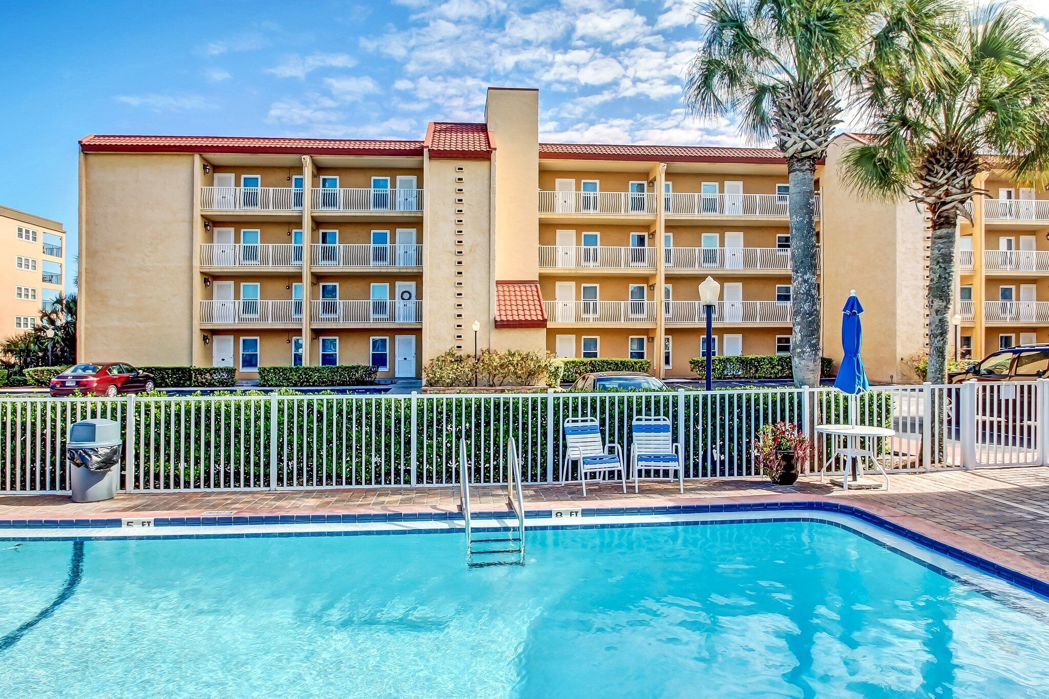 Un hotel con piscina, varios balcones y palmeras.
