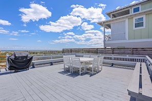 A wooden deck with a table and chairs, a covered grill, and a view of the ocean. - 2958 S Fletcher Ave (Fernandina Beach)
