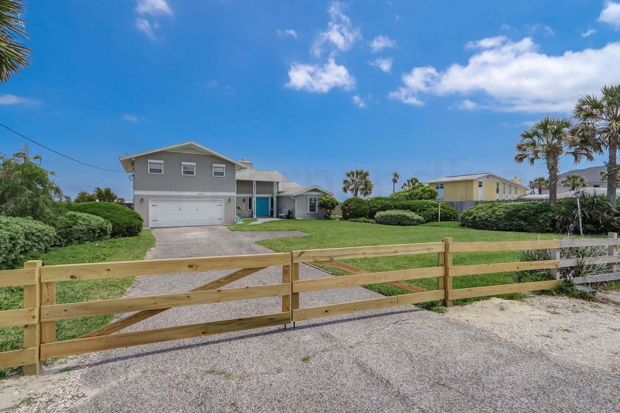 A residential property with a two-story house, a driveway, and a wooden fence.