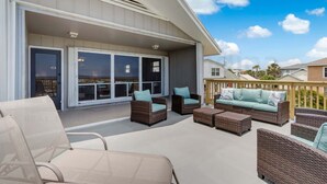 Ein Außenbereich mit Terrassenausstattung aus Rattan, einer Schiebetür und einem Holzboden.