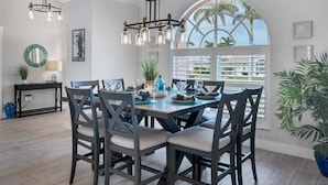 Comedor con una gran mesa, sillas e iluminación colgante.