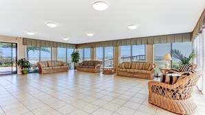 A spacious living area with wicker furniture, large windows, and a tiled floor. - 6th Floor, Oceanfront Condo Easy Beach Access via Boardwalk & Exclusive Fishing Pier (Fernandina Beach)