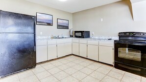 A kitchen with white cabinets, a black refrigerator, a microwave, and an oven. - 6th Floor, Oceanfront Condo Easy Beach Access via Boardwalk & Exclusive Fishing Pier (Fernandina Beach)