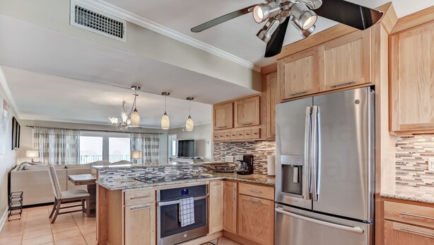 A modern kitchen with wooden cabinets, stainless steel appliances, and pendant lighting. - 6th Floor, Updated and Beautiful! Oceanfront Condo With Balcony, Fishing Pier (Fernandina Beach)