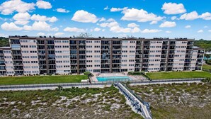 A multi-story residential building with a swimming pool and a grassy area in front.