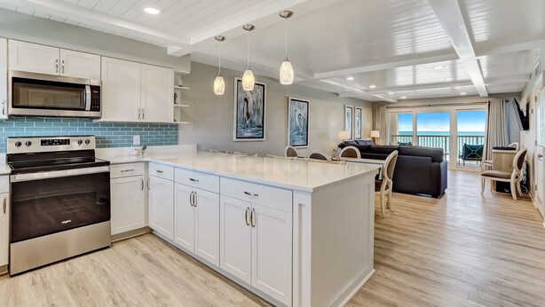 A modern kitchen with white cabinets, a stainless steel oven, and pendant lights.