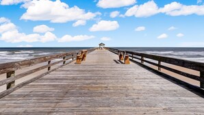 A wooden pier extending into the ocean with a gazebo at the end.