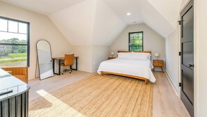 A bedroom with a sloped ceiling, a bed, a desk, and a chair.