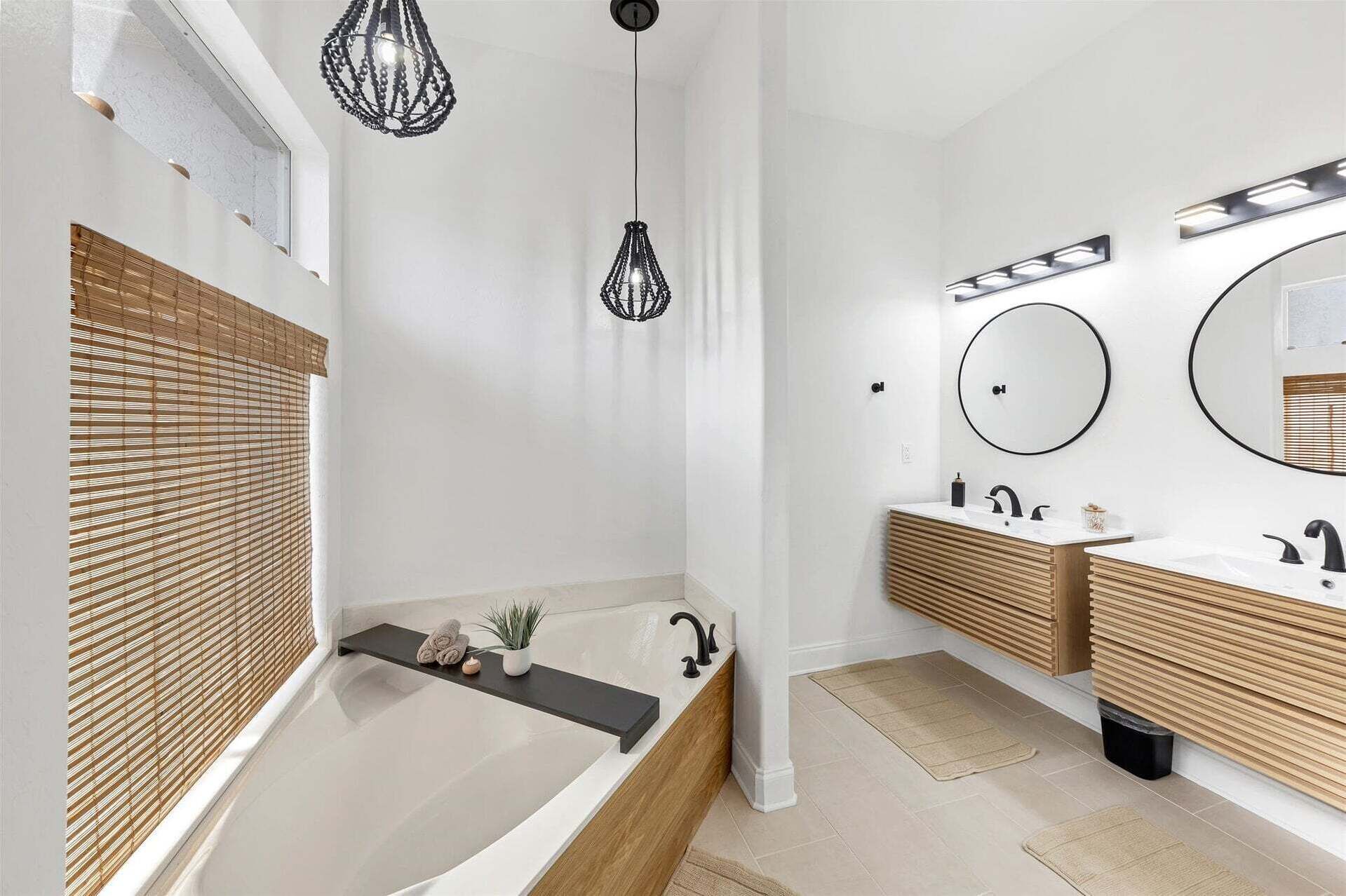 Une salle de bain moderne avec une baignoire, deux lavabos et des luminaires suspendus.