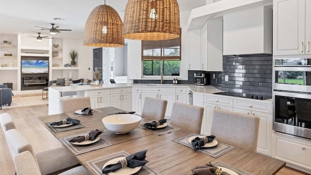 A modern kitchen with white cabinetry, a large island, and a dining area with a wooden table set for six. - Fpc228 (Punta Gorda)