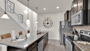 A modern kitchen with granite countertops, stainless steel appliances, and a clock on the wall. - Rhs9030 (Kissimmee)