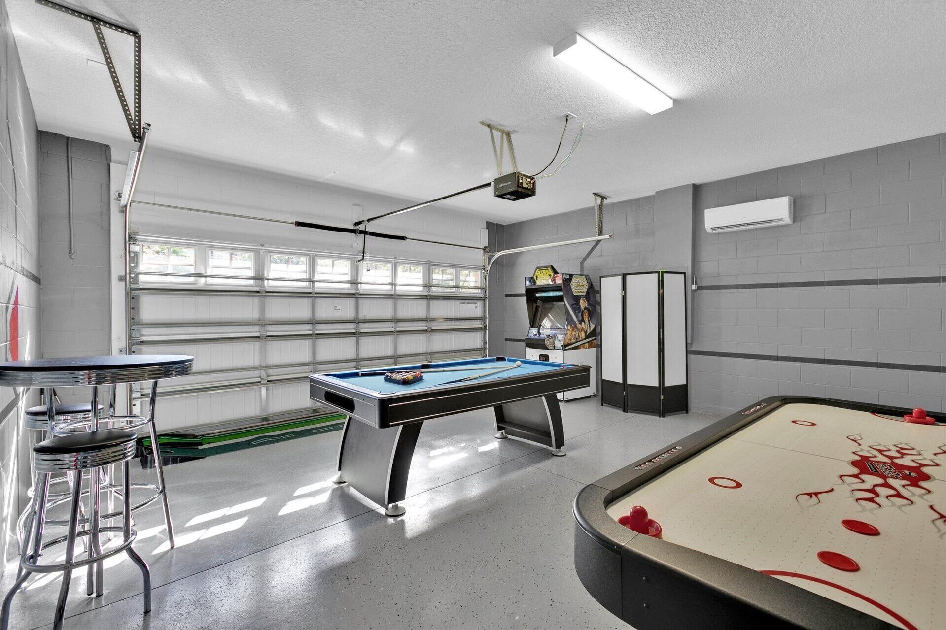 A billiards room with a pool table, a bar area, and a dartboard.