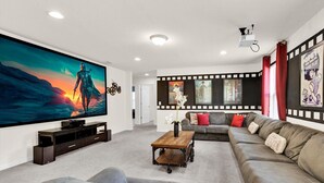 A modern living room with a large flat-screen TV, a grey sofa, and a coffee table. - Rhs9030 (Kissimmee)