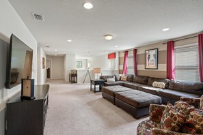 Un salón amplio con un sofá modular grande, un televisor de pantalla plana y una mesita auxiliar pequeña.