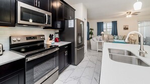 Une cuisine moderne dotée d’un four à micro-ondes, d’un four et d’un réfrigérateur encastrés, d’un plan de travail blanc et d’un sol en marbre.