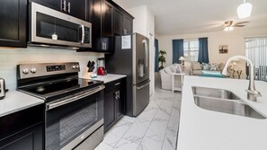 Eine moderne Küche mit integriertem Mikrowellenherd, Backofen und Kühlschrank, einer weißen Arbeitsplatte und einem Marmorboden.
