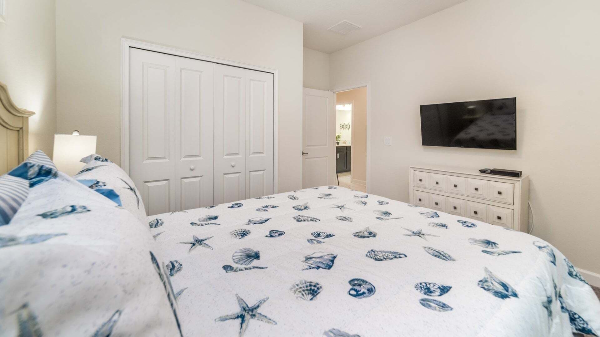 Een slaapkamer met een bed, een televisie, een dressoir en een inloopkast.