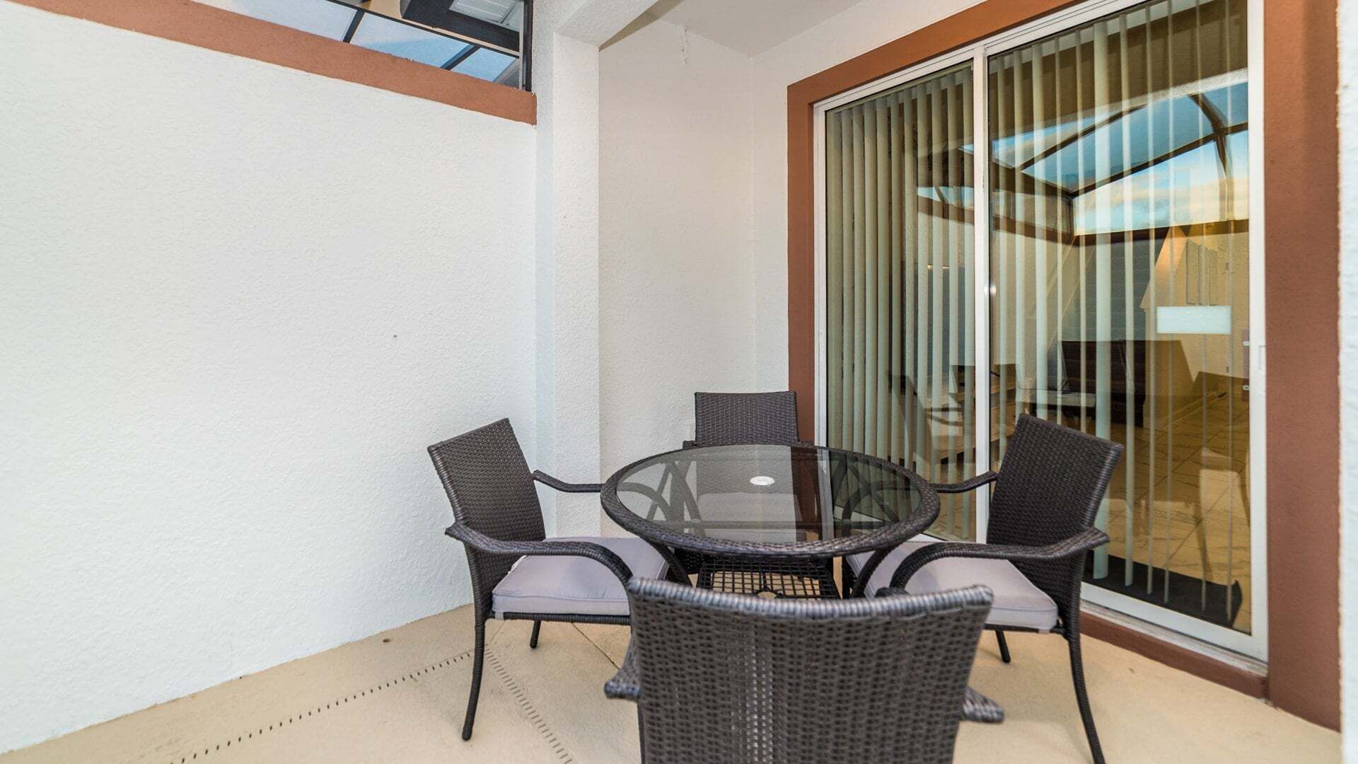 Ein Tisch mit Glasplatte, vier Stühle, eine Glastür und eine weiße Wand.