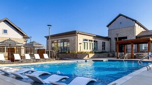 Ein Schwimmbecken mit Liegestühlen und ein Gebäude mit großen Fenstern.