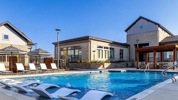 A swimming pool with lounge chairs and a building with large windows. - Relaxing Getaway, Worker-friendly, A+ Location (Sherman)