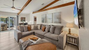Amplia sala de estar con un sofá modular grande, ventilador de techo y vistas al exterior.