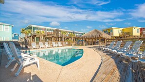 Un espace piscine comprenant des chaises longues, une piscine et un bâtiment doté de nombreux balcons.
