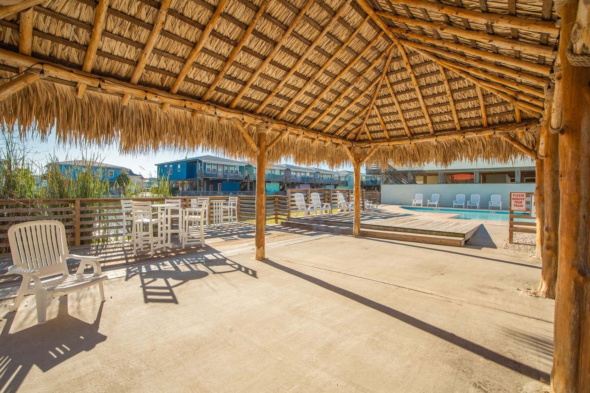 A covered outdoor area with a pool, lounge chairs, and a wooden deck.