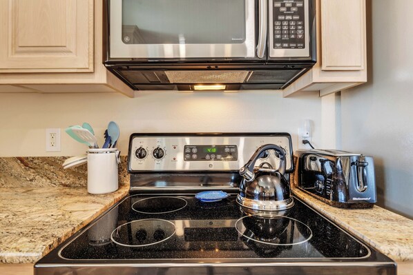 A kitchen with a black stovetop, a microwave, a toaster, and a kettle. - Oasis (Yucca Valley)