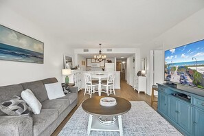 Ein modernes Wohnzimmer mit grauem Sofa, Couchtisch und Fernseher auf einem Schrank.