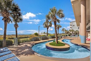 Ein Poolbereich mit Liegestühlen, Palmen und Blick auf den Strand.