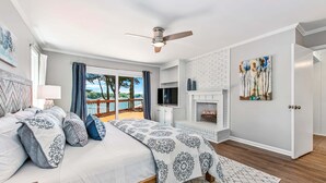 A bedroom with a bed, a ceiling fan, a TV, a fireplace, and a balcony with a view. - Normandy Approach (Mooresville)