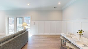 A modern living room with a grey sofa, a dining table set with white plates and cutlery, and a lamp on a side table. - Saw Mill 90 - 8 A (Sunset Beach)