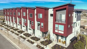 Une rangée d’immeubles modernes à plusieurs étages, aux couleurs rouge et blanche, dotés de balcons et de grandes fenêtres.