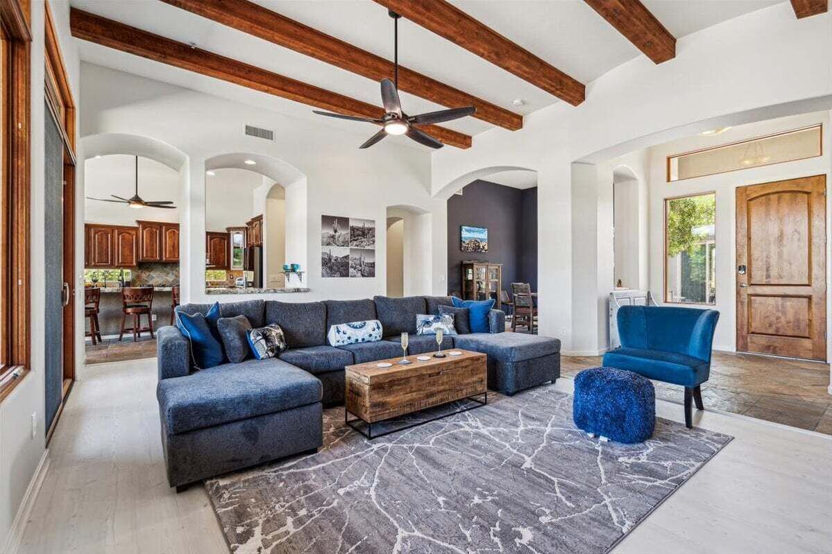 A spacious living room with a sectional sofa, a coffee table, and a blue chair.