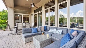 Une terrasse extérieure avec un canapé, des fauteuils et une table.