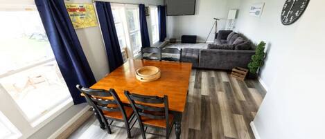 A compact living space with a dining table, chairs, a sofa, and a TV.