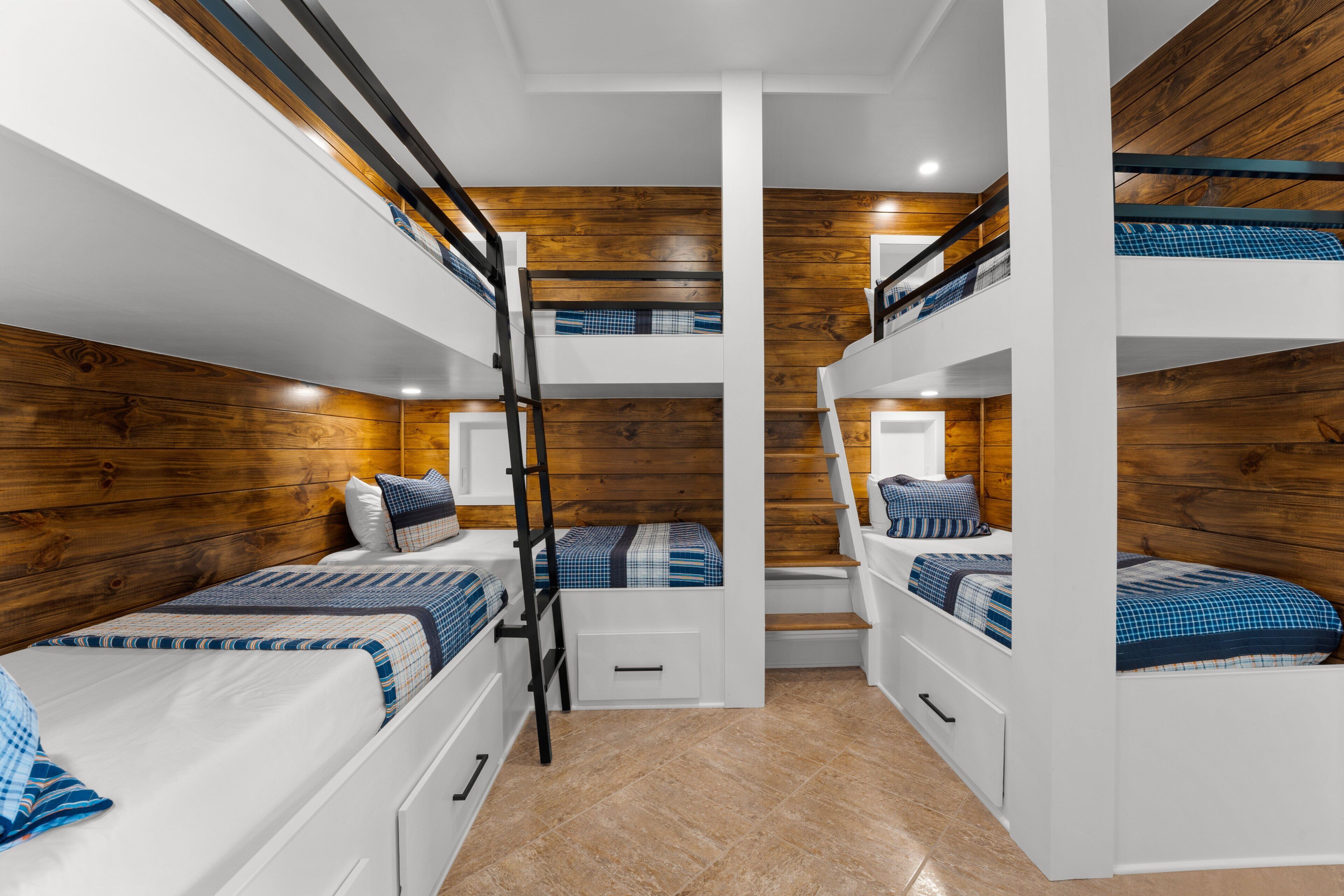 A bunk bed room with wooden walls, white beds, and a ladder.