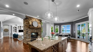 A spacious kitchen with a stone fireplace, granite countertops, and pendant lighting. - Sunset on Ballycastle (Mooresville)