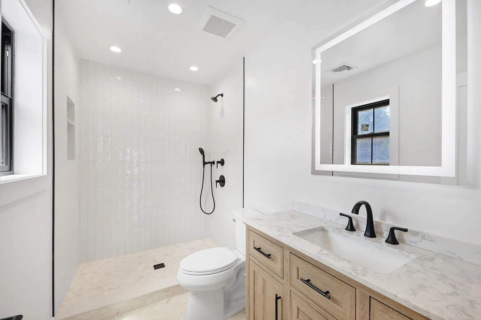 A modern bathroom with a shower, toilet, and vanity with a mirror.