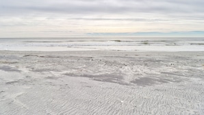 En strand med en sandstrand och en molnig himmel.